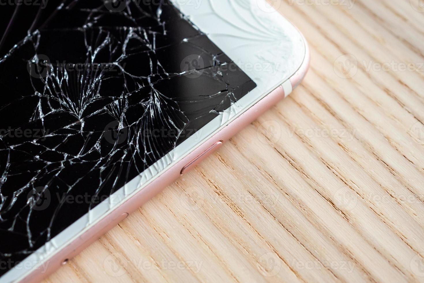 broken glass of mobile phone screen on wooden background photo