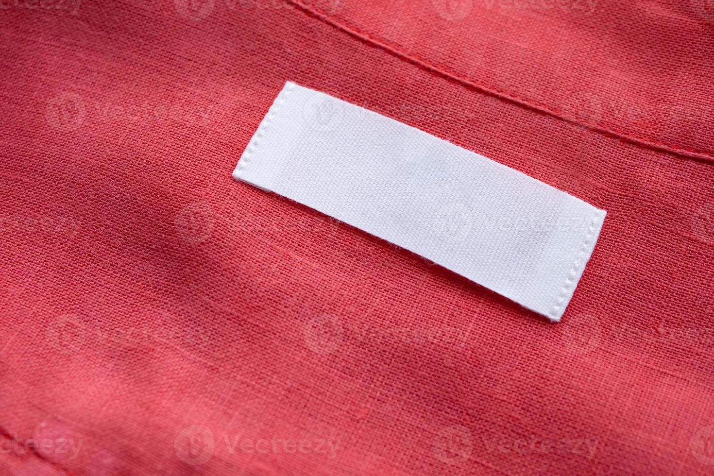 White blank clothing tag label on red linen shirt fabric texture background photo