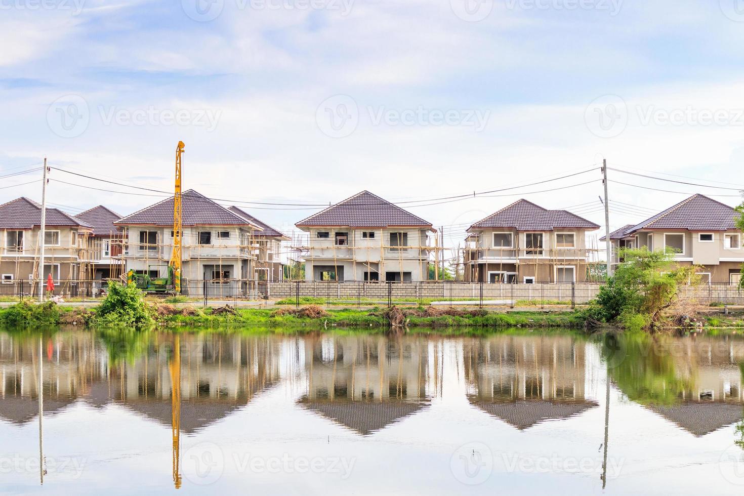 New house building reflection with water in lake at residential estate construction site with clouds and blue sky photo