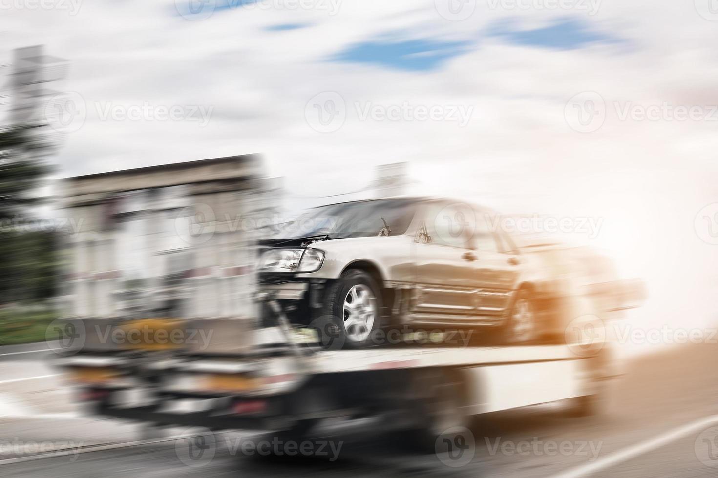 Broken car on tow truck after traffic accident, on the road service photo