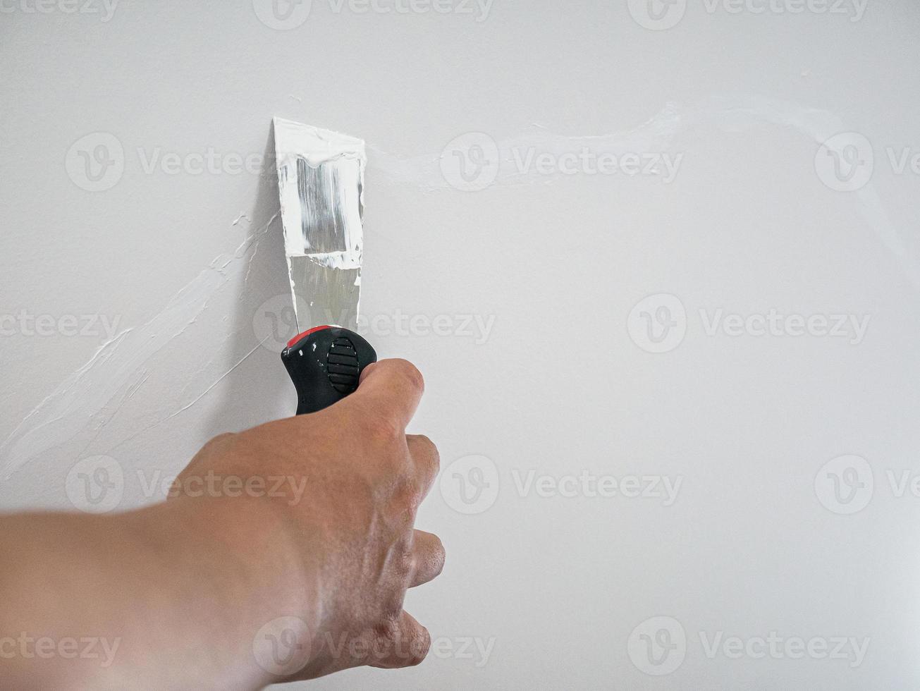 Plasterer hand repair crack white wall photo