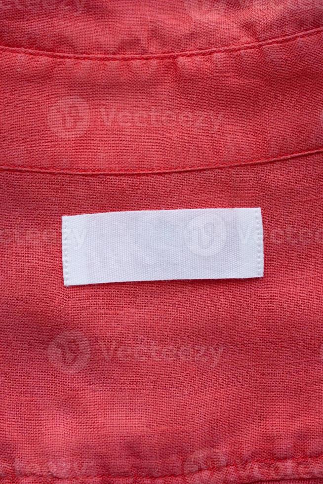 White blank clothing tag label on red linen shirt fabric texture background photo