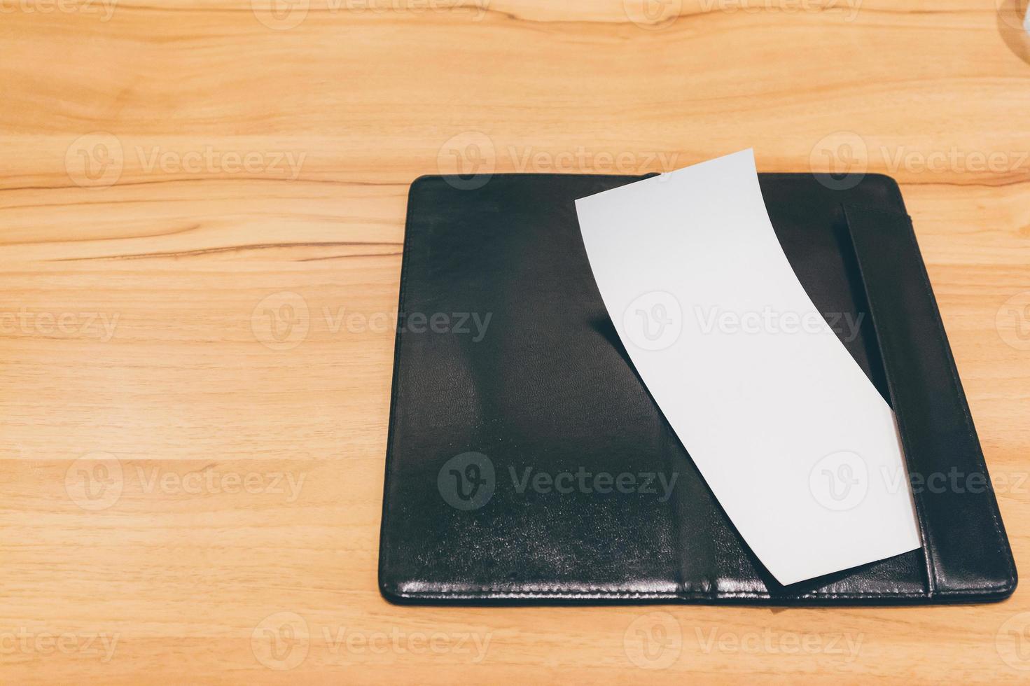 Blank empty white paper in restaurant payment billing receipt folder on wood table photo