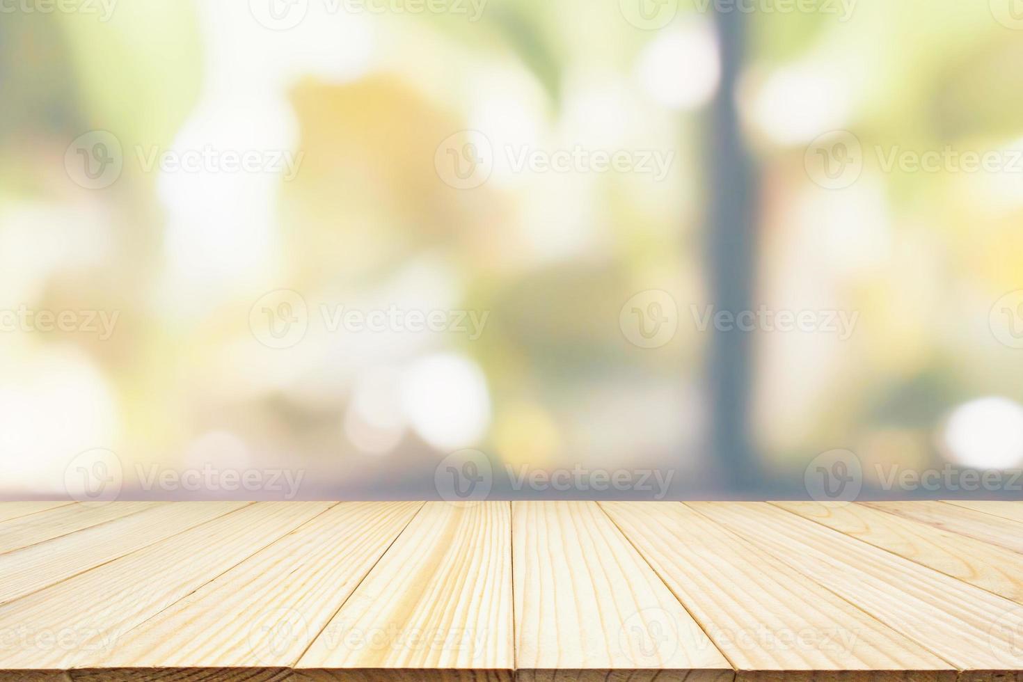 Empty wooden table top with green garden at cafe restaurant or coffee shop window abstract blur defocused with bokeh light background for montage product display photo