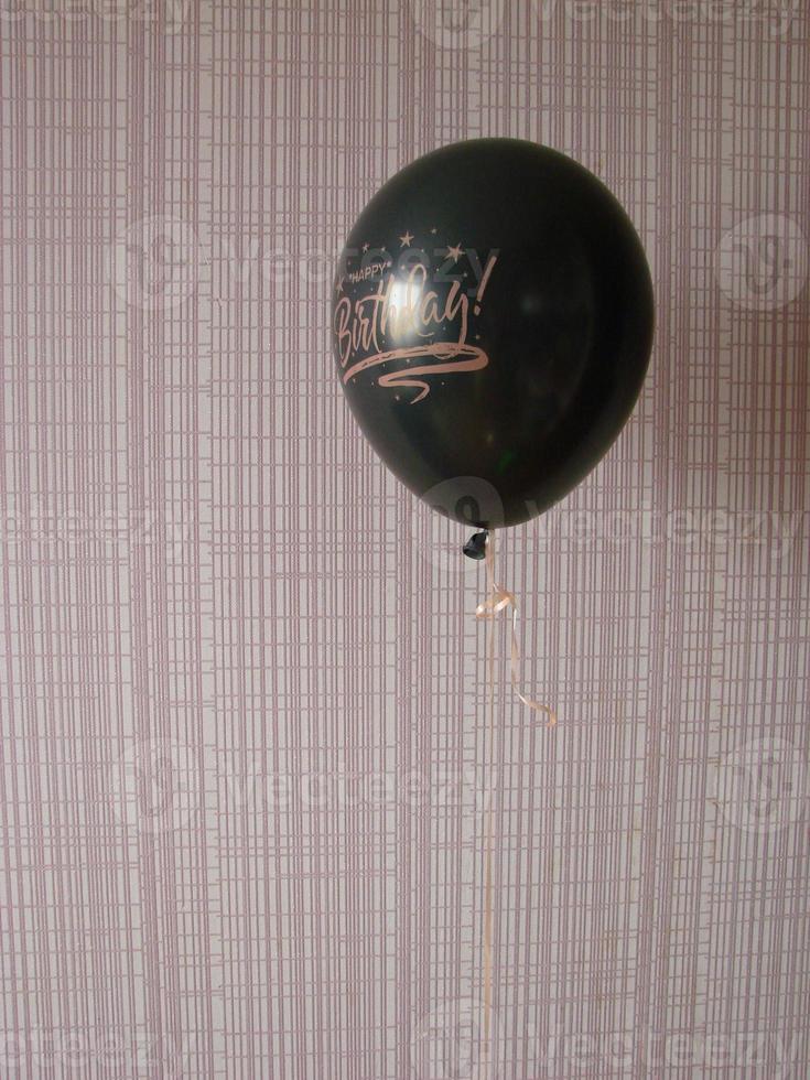 Black balloon with words HAPPY BIRTHDAY on yellow background, space for text photo