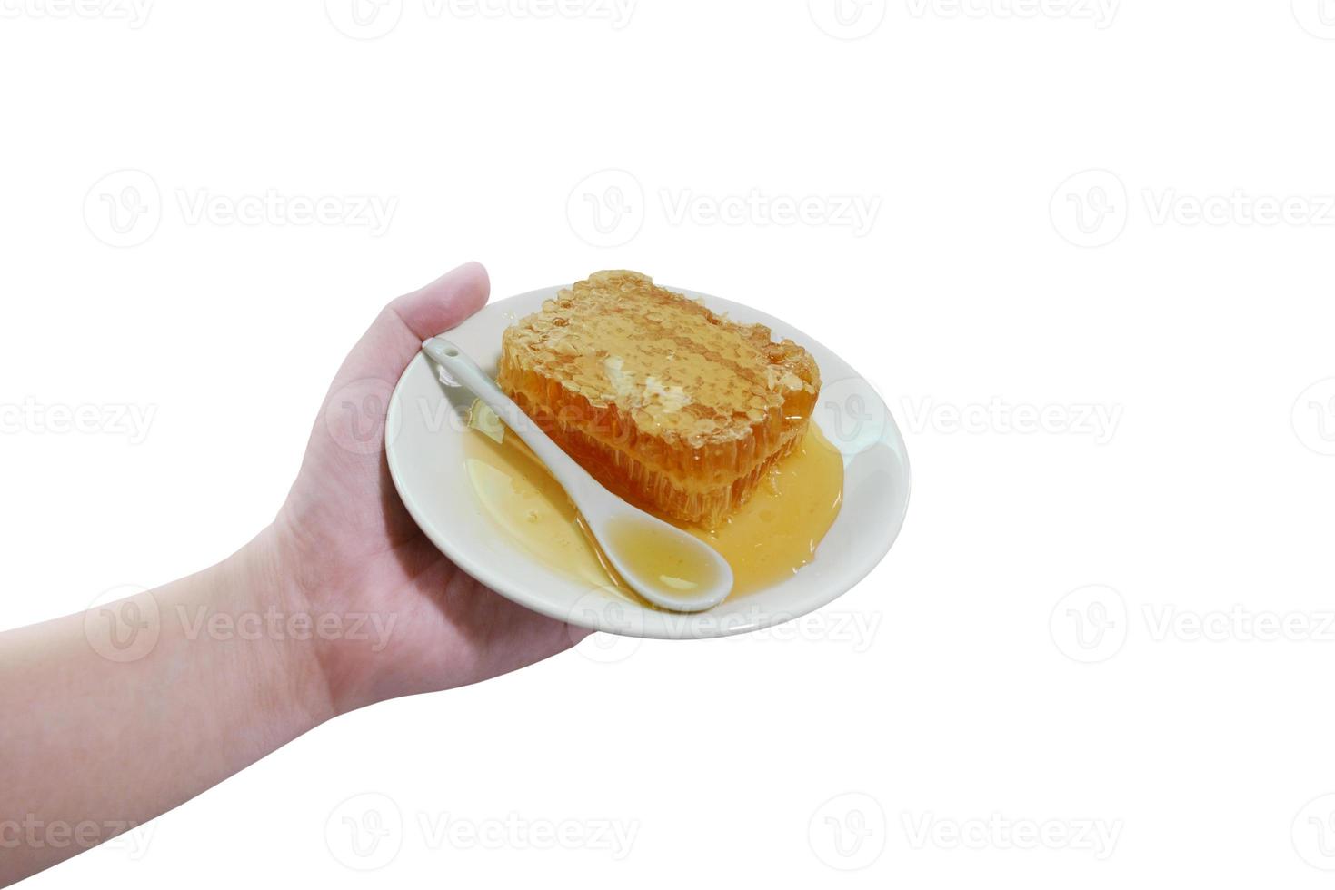 Honeycomb on a plate in hand on a white background . Honey flows out of a honeycomb into a plate. photo