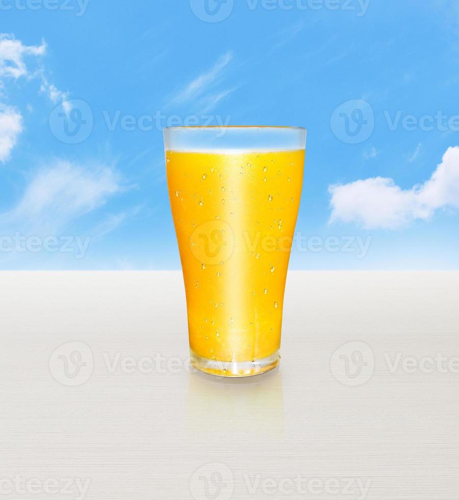 jugo de naranja en un vaso de vitamina c. útil en una mesa de madera blanca. con el cielo de fondo foto