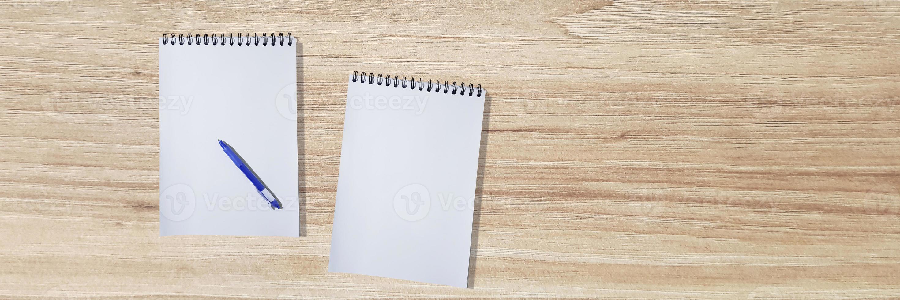 An empty notebook with a pen is placed on a wooden table. top view with text input area photo