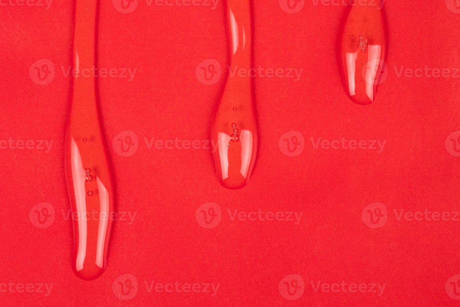 transparent varnish, clear oil drops on red paper copy space background photo