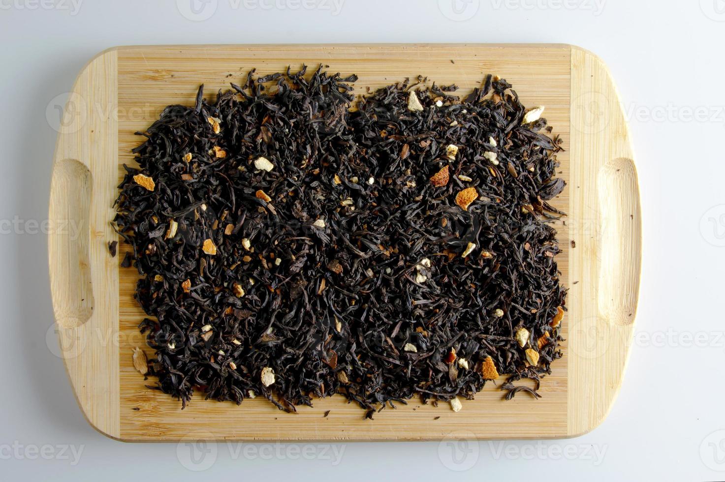 Background of fragrant black tea leaves with dried citrus slices and peel. Tea on a wooden board. Dry texture of black tea photo