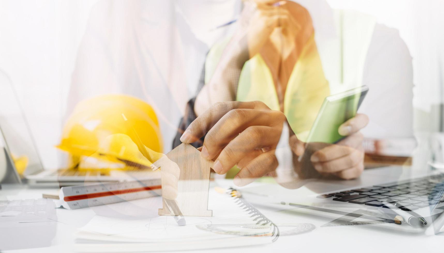 Two colleagues discussing data working and tablet, laptop with on on architectural project at construction site at desk in office photo