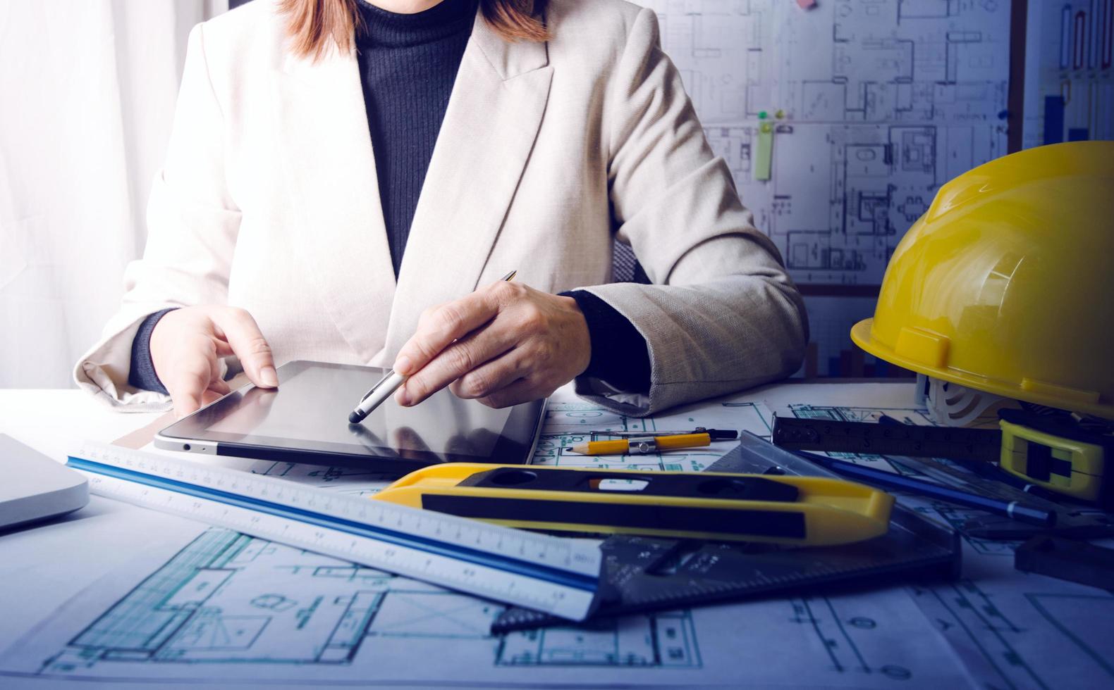 Two colleagues discussing data working and tablet, laptop with on on architectural project at construction site at desk in office photo