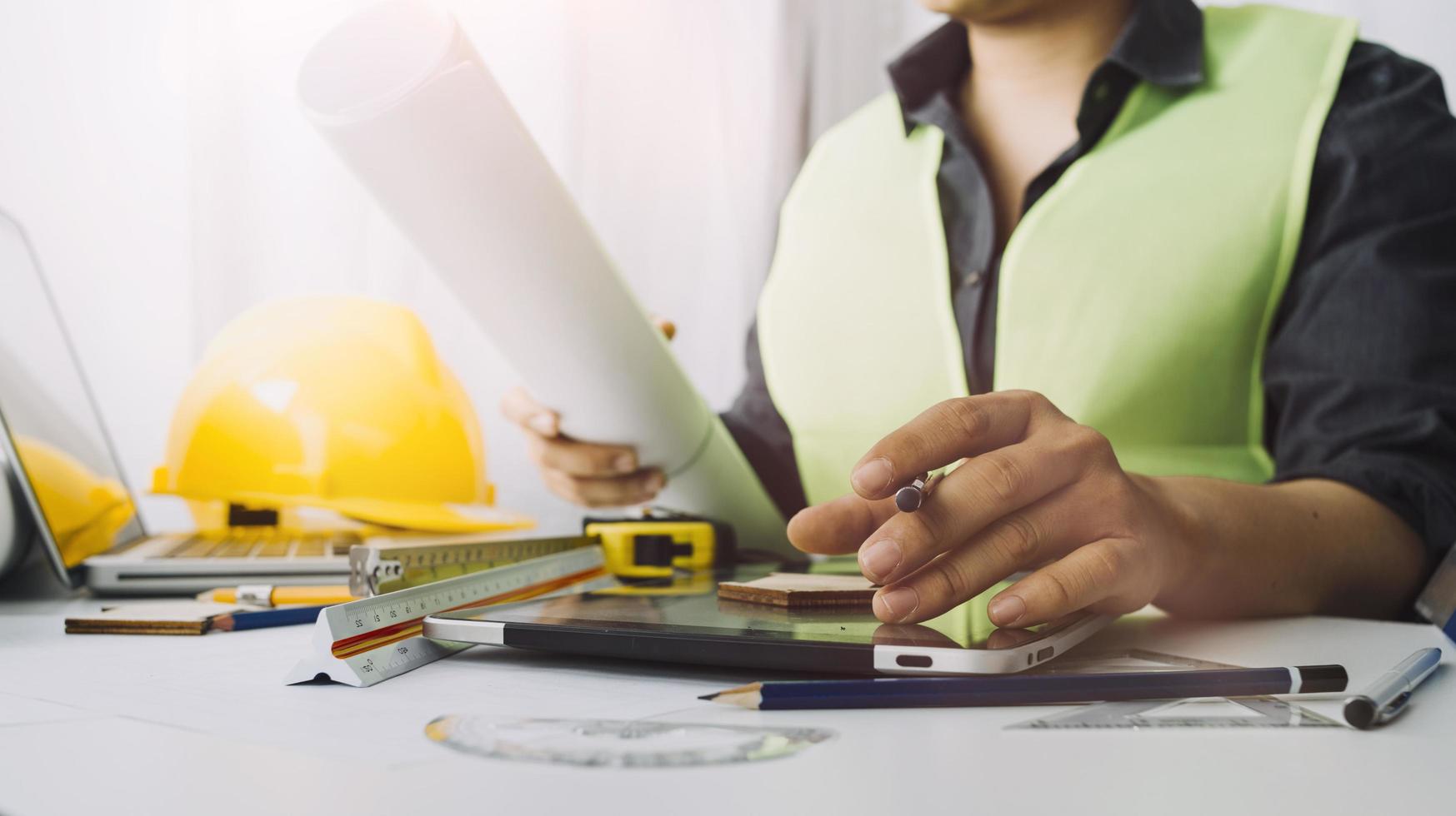 Two colleagues discussing data working and tablet, laptop with on on architectural project at construction site at desk in office photo