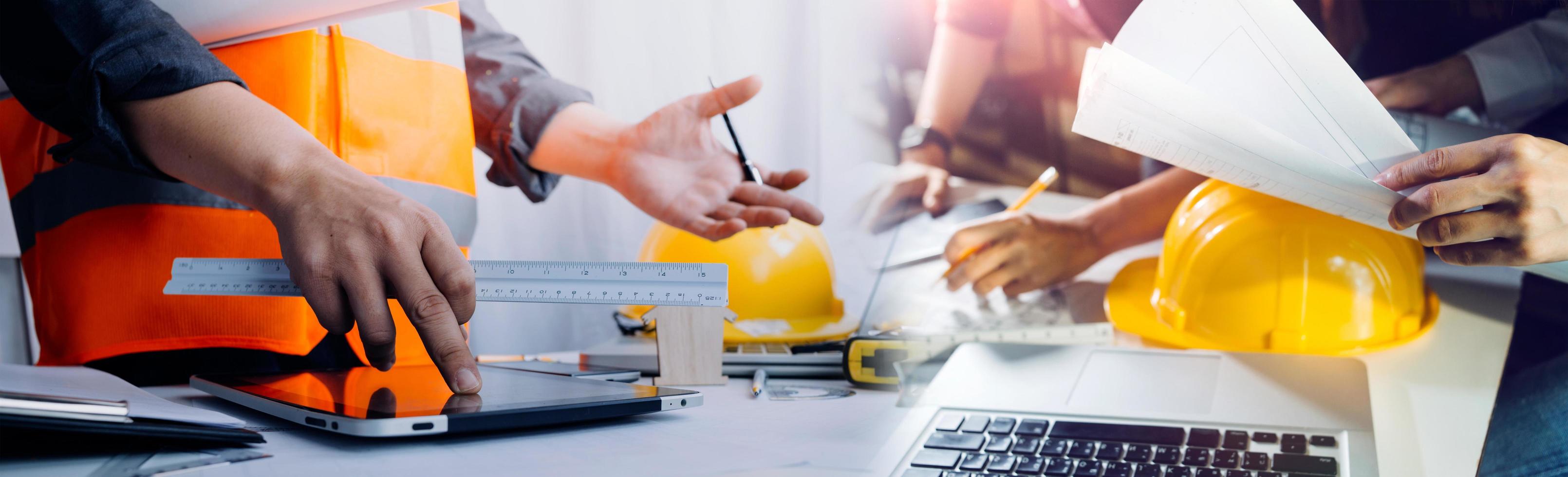 Two colleagues discussing data working and tablet, laptop with on on architectural project at construction site at desk in office photo