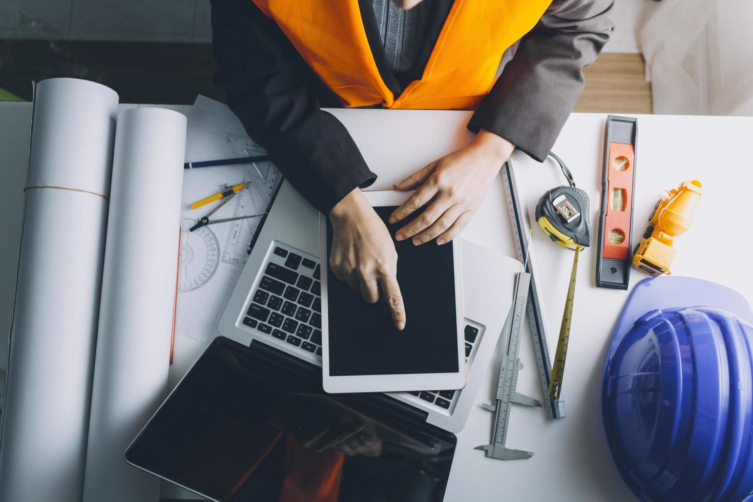 Dos colegas discutiendo el trabajo de datos y una tableta, un portátil con un proyecto arquitectónico en el sitio de construcción en un escritorio en la oficina foto