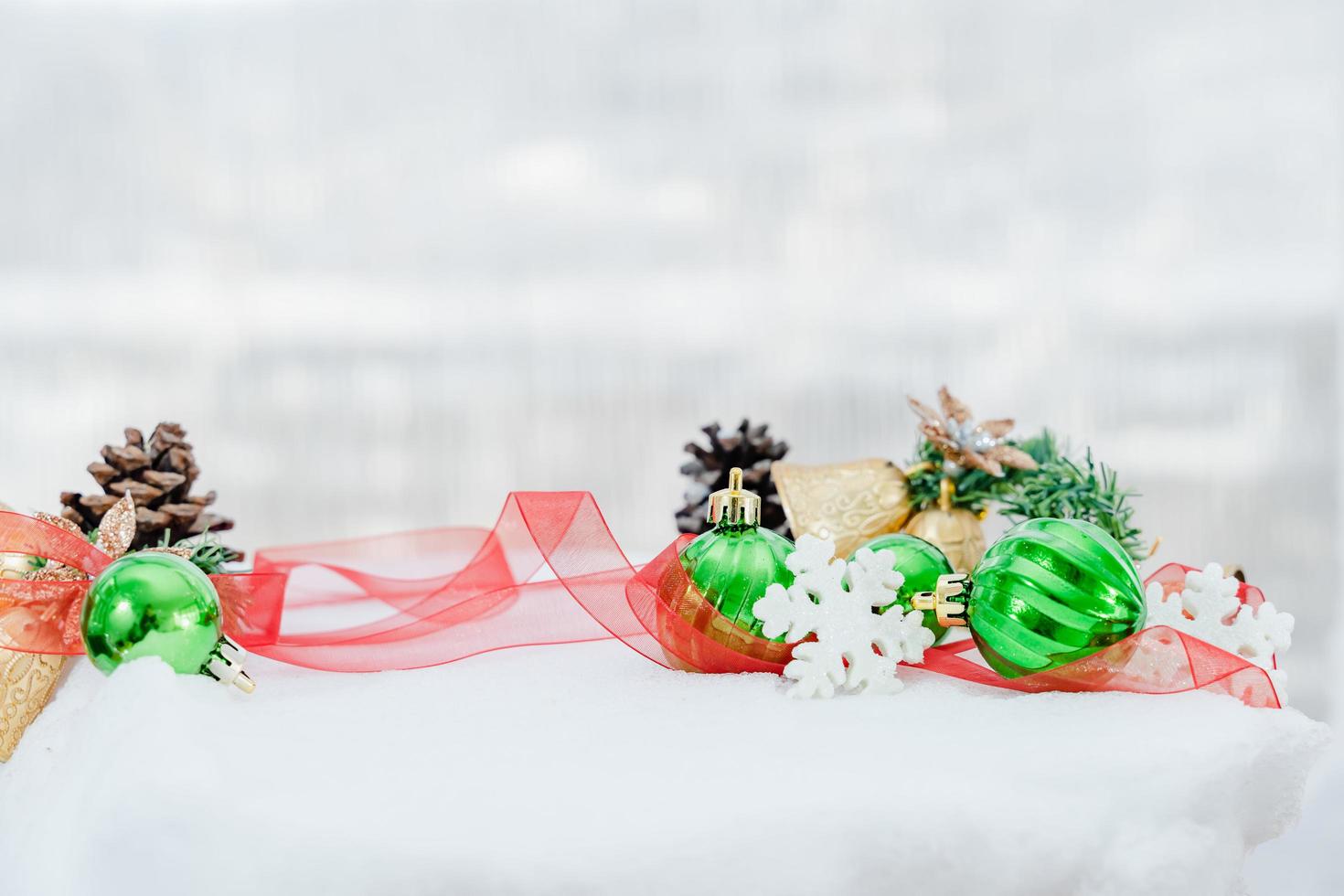 navidad de invierno - bolas de navidad con cinta en la nieve, concepto de vacaciones de invierno. bolas verdes de navidad, bolas doradas, decoraciones de pino y copos de nieve en el fondo de la nieve foto