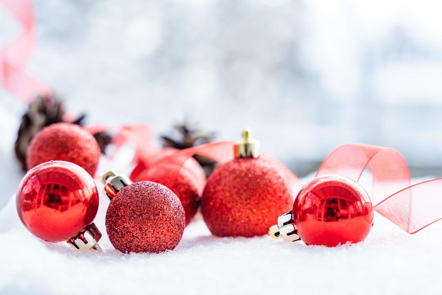 navidad de invierno - bolas de navidad con cinta en la nieve, concepto de vacaciones de invierno. bolas rojas de navidad, bolas doradas, decoraciones de pino y copos de nieve en el fondo de la nieve foto