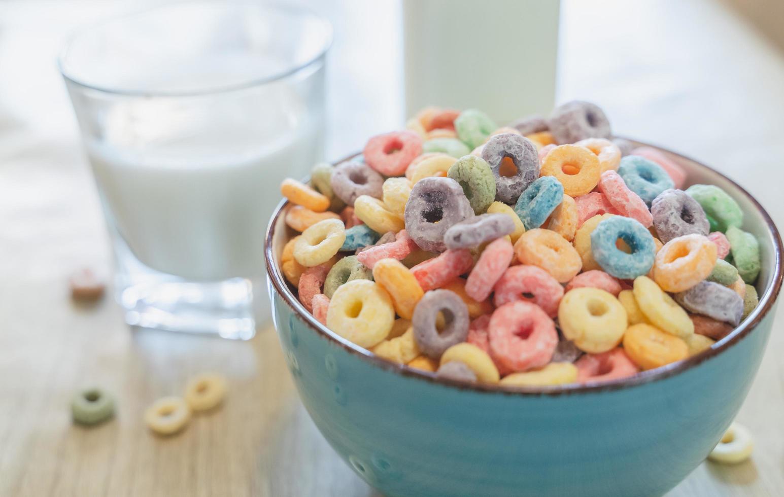 Tazón de coloridos cereales y leche para niños aislado en una mesa de madera con espacio de texto foto