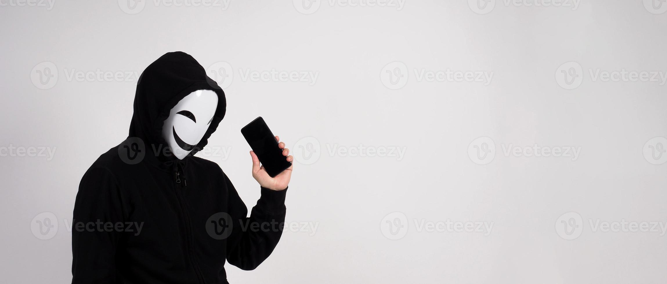 hacker anónimo y mascarilla con smartphone en la mano. foto