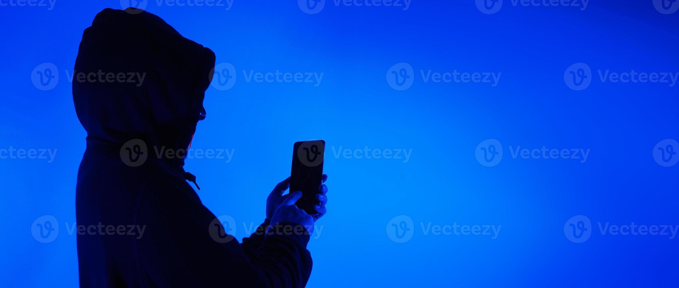 Digital security Concept. Anonymous hacker with mask holding smartphone hacked. photo
