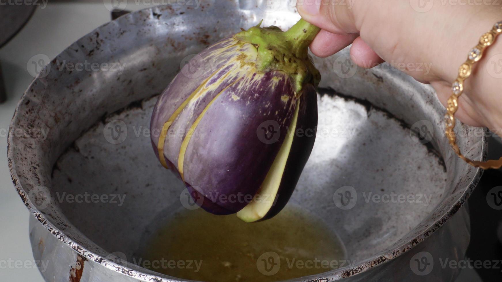 berenjena entera fresca o berenjena traída, berenjena morada cocida al vapor con especias y hierbas para congelar y conservar para cocinar más tarde foto