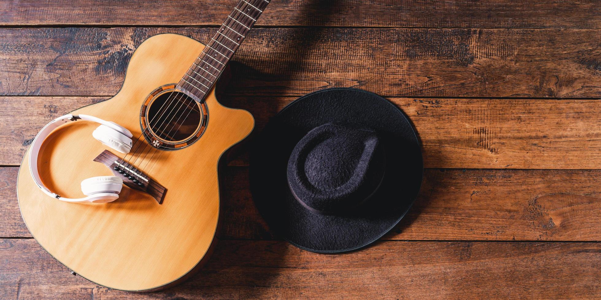 Top view acoustic guitars with earphones and hipster hats on old wooden background.Flat lay photo