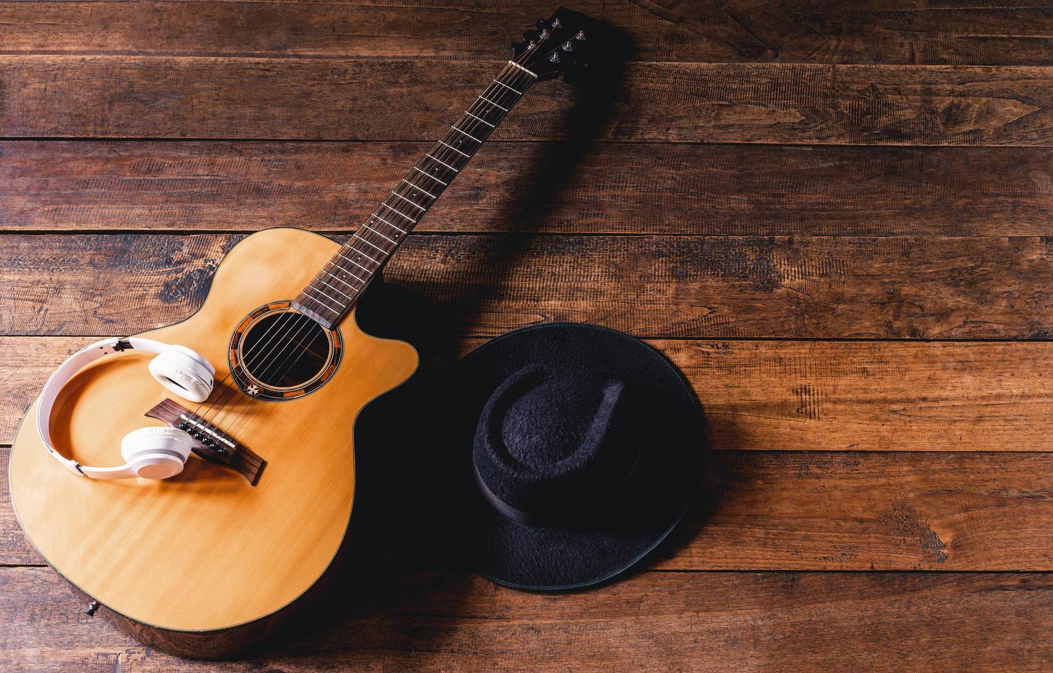 Top view acoustic guitars with earphones and hipster hats on old wooden background.Flat lay photo