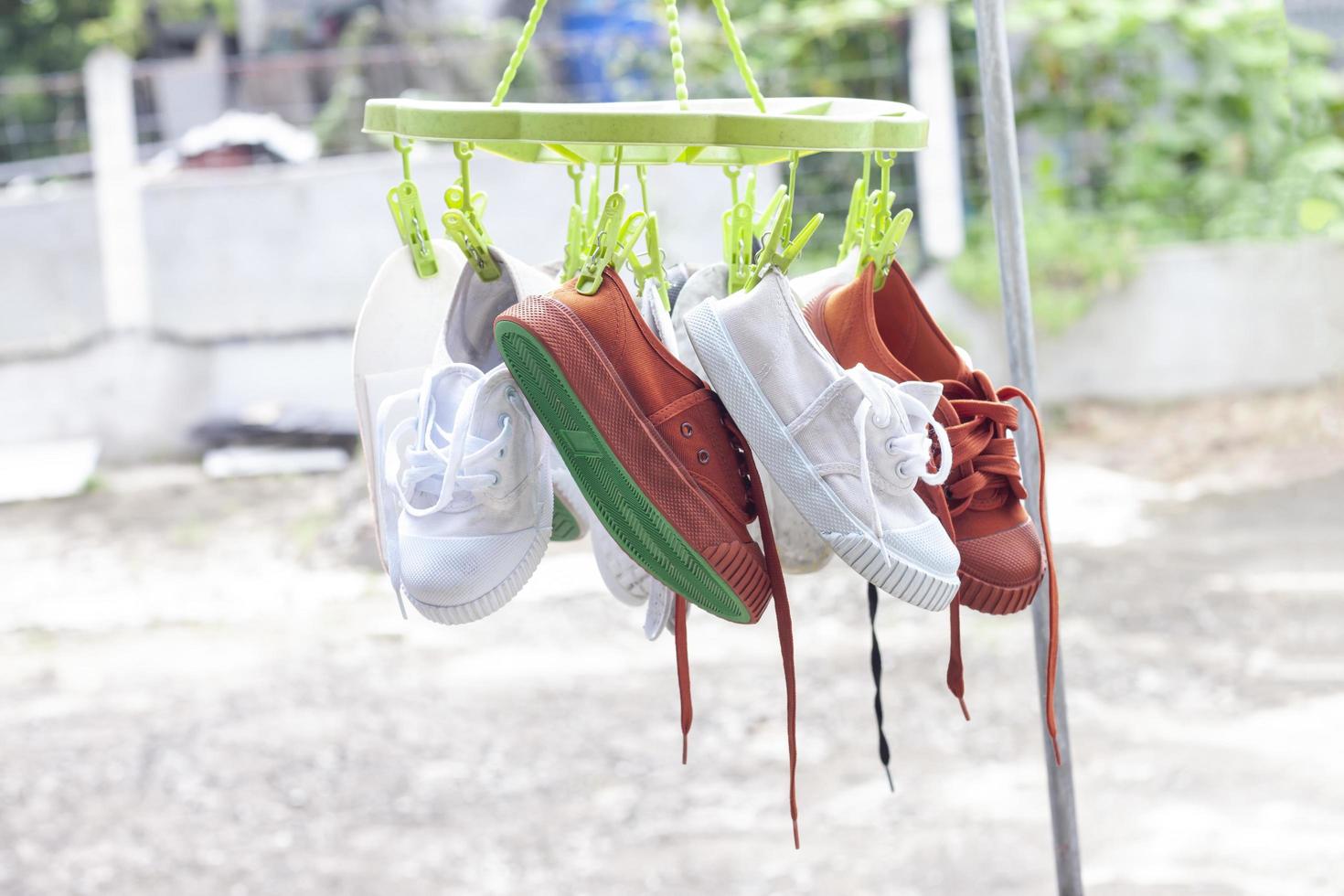 White and brown student sneakers that are washed and hanging to dry in the sun. photo