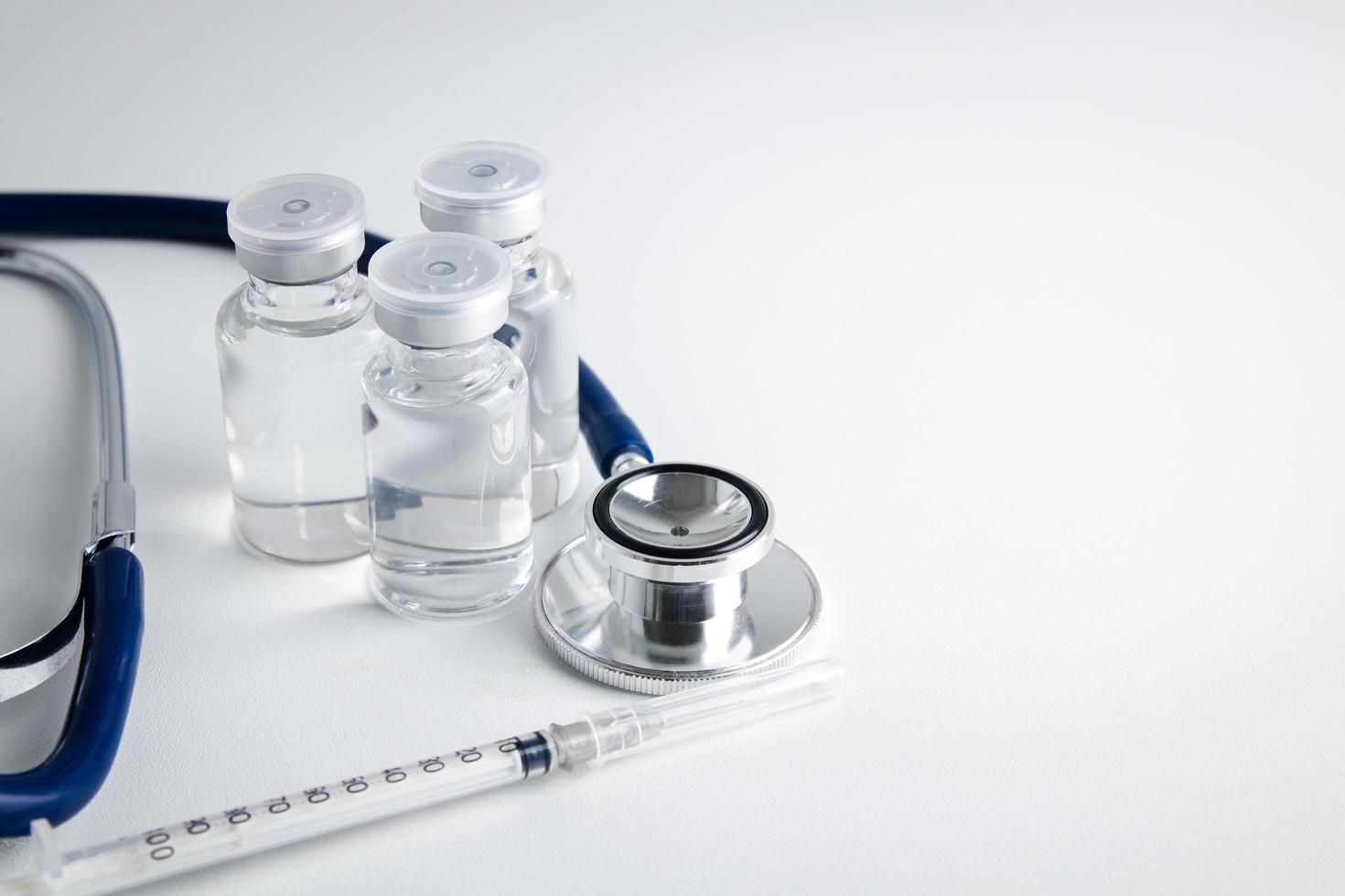 Anti-virus vaccine bottle with syringe And stethoscope Placed on a white background Concept of vaccine for the coronavirus, or COVID-19. Hospital medical services. Copy space photo