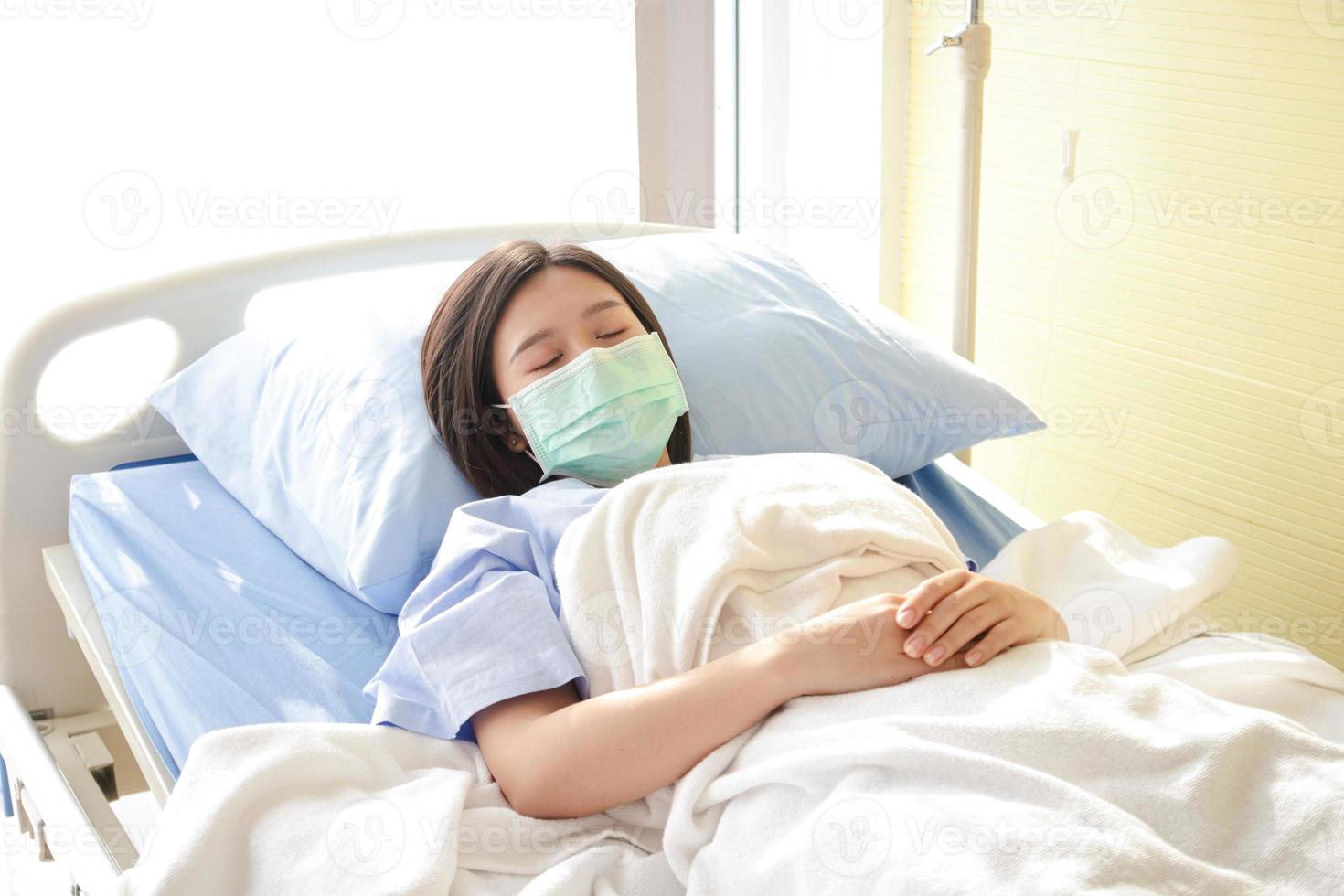 Asian female patients Wear a blue mask and lie in a hospital bed. Have a sickness from the coronavirus. Concept of medical services, health insurance photo