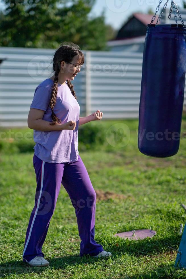 niña golpeando saco de arena. entrenamiento de boxeo muay thai. niña sana golpeando en el saco de boxeo. concepto de entrenamiento de boxeo, ejercicio, ejercicio físico, deporte foto