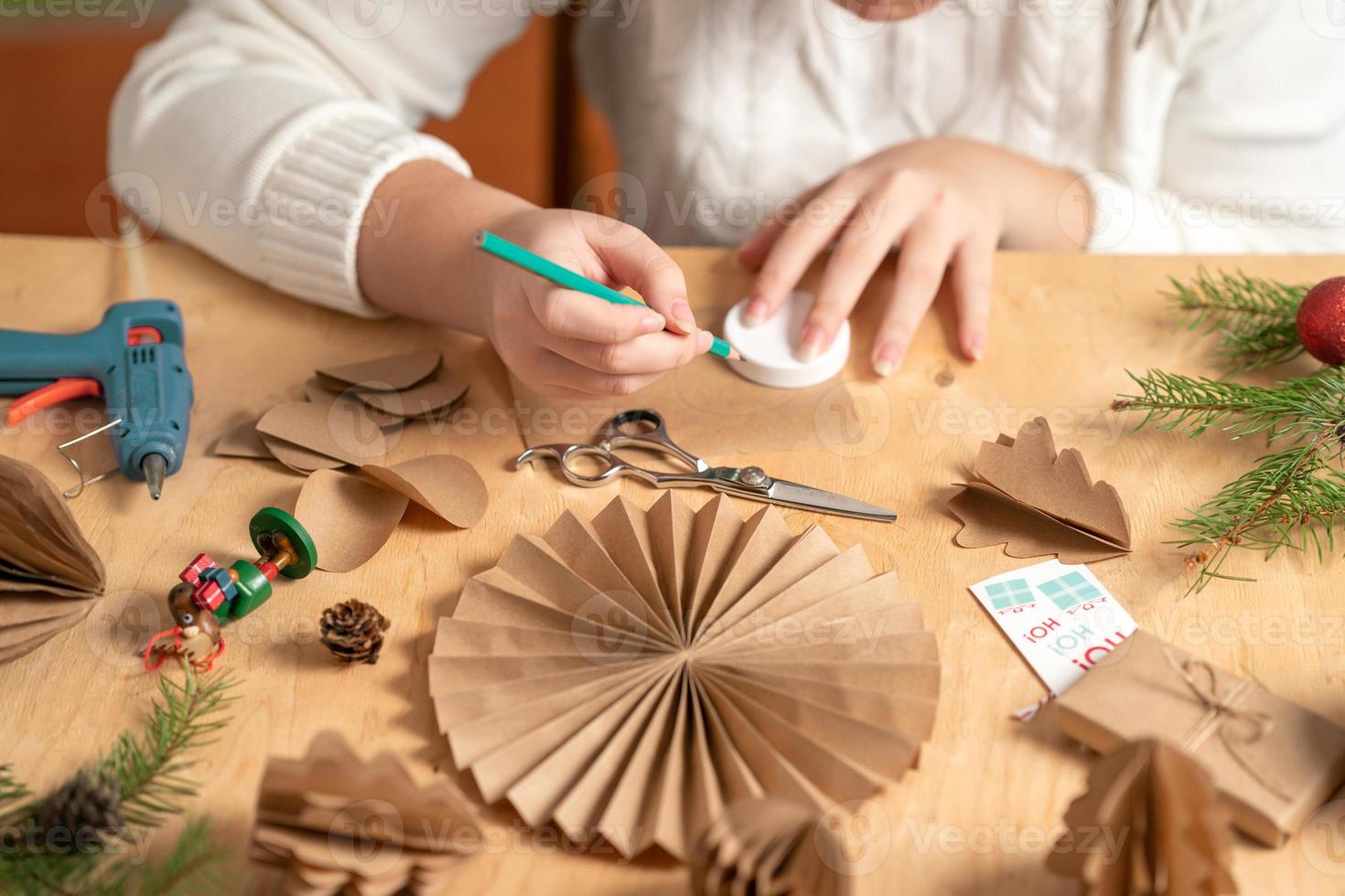girl makes Christmas tree decorations out of paper with her own hands. step 1. step-by-step instruction photo
