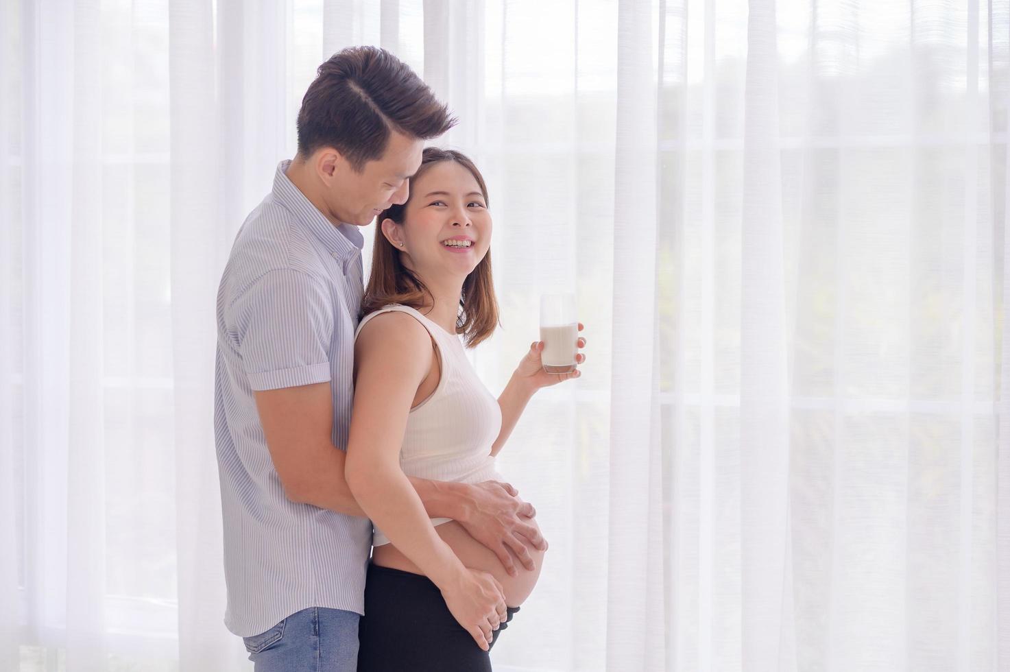 marido asiático abrazando a su esposa que está a punto de beber leche fresca con amor foto