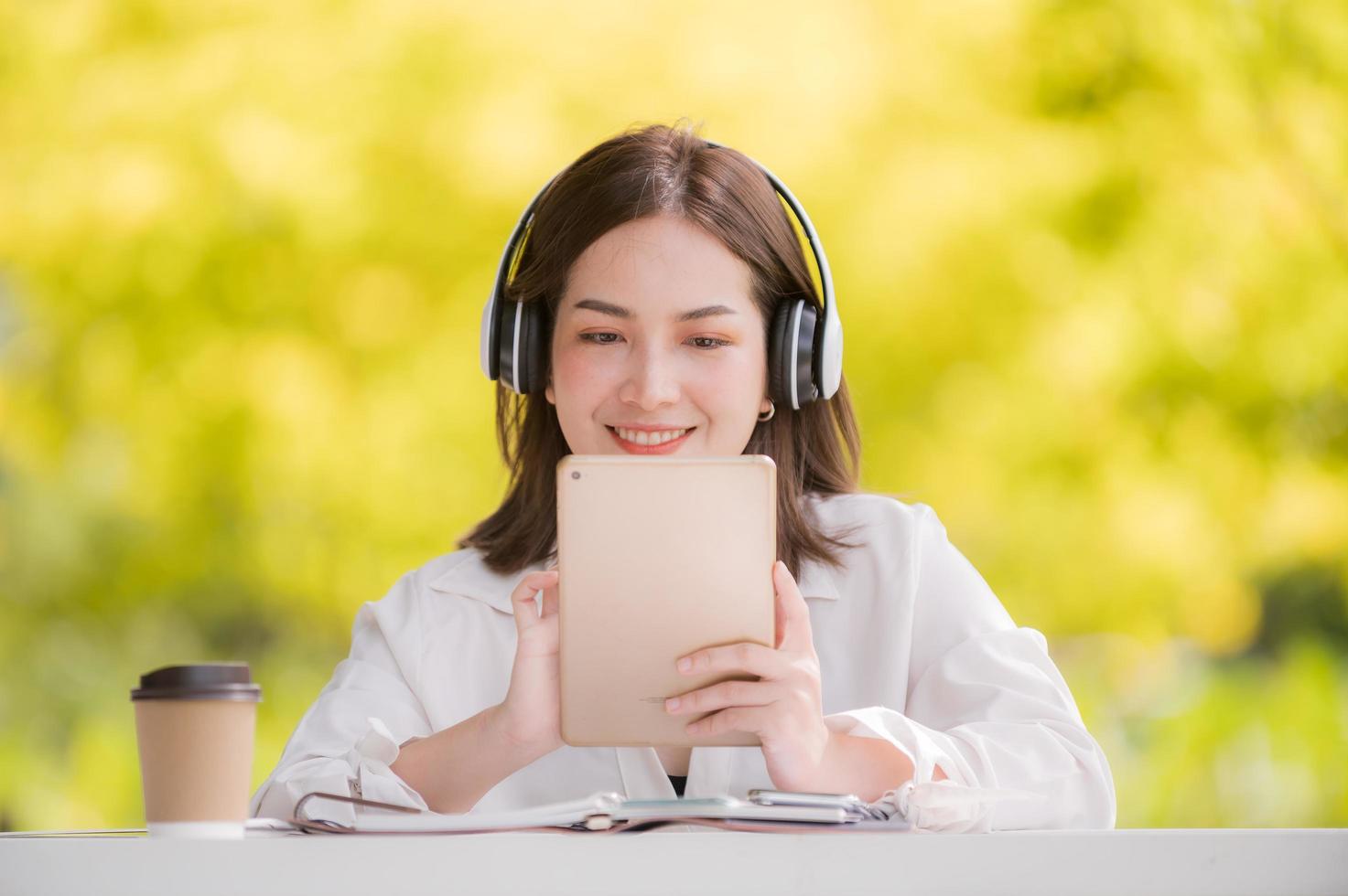 A beautiful Asian woman relaxing in the back garden with headphones connecting via the Internet for online work and study photo