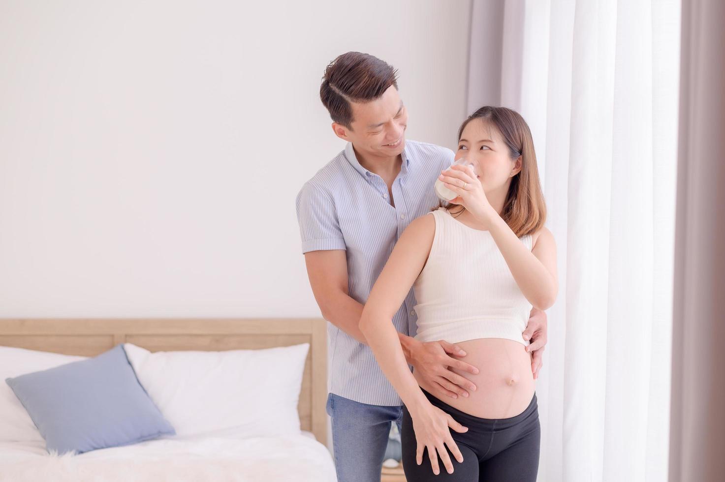 marido asiático abrazando a su esposa que está a punto de beber leche fresca con amor foto