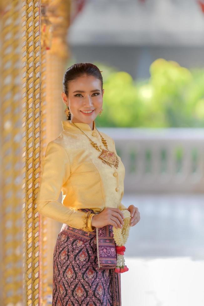 Attractive Thai woman in an ancient Thai dress holds a fresh garland paying homage to Buddha to make a wish on the traditional Songkran festival in Thailand photo