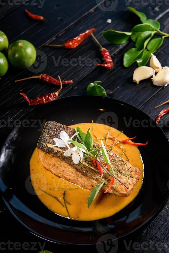 Pork red curry served and decorated with vegetables, herbs and spices on rustic background - Thai food photo