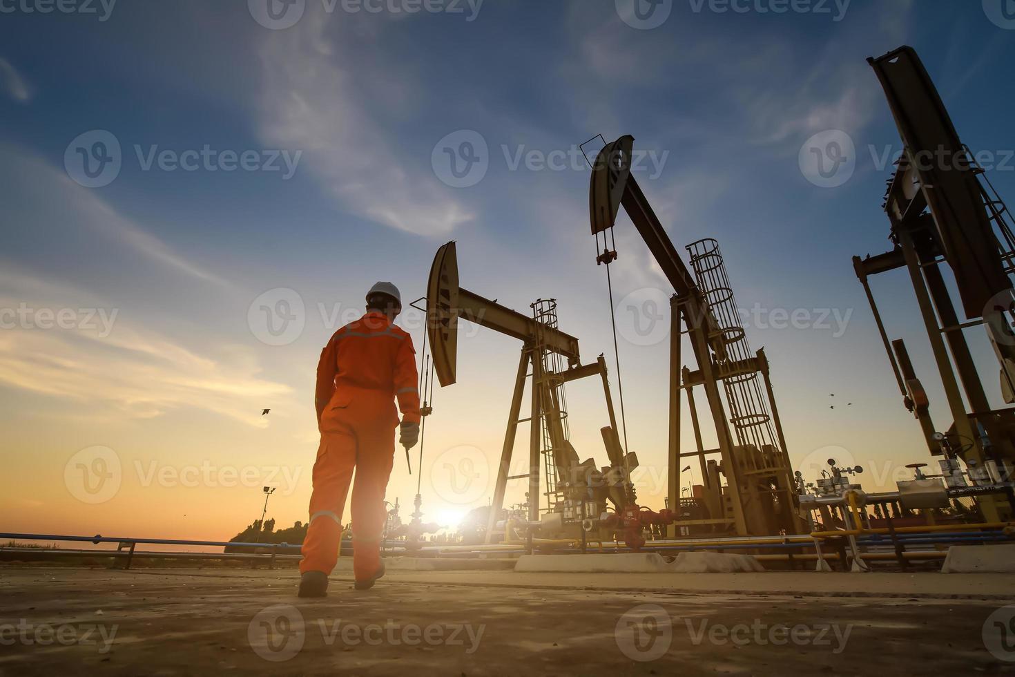 silueta de trabajadores petroleros que trabajan en plataformas petrolíferas o campos petroleros y gasolineras por la noche con una hermosa puesta de sol. foto