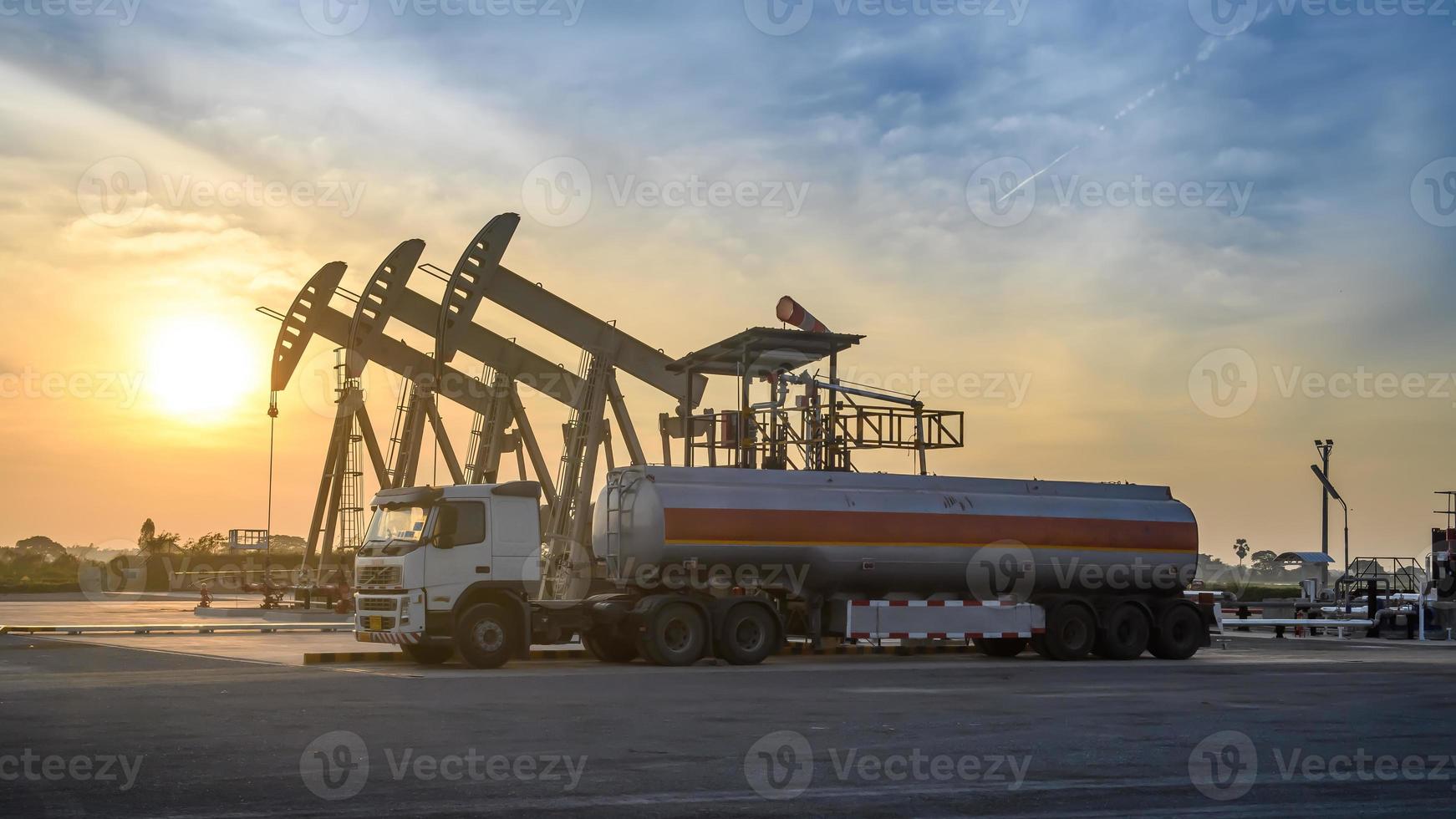 Oil field site, in the evening, oil pumps and oil truck photo