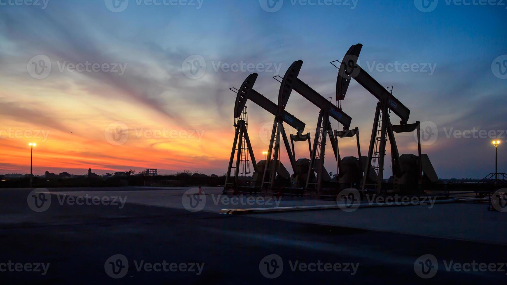 Oil field site, in the evening, oil pumps are running, The oil pump and the beautiful sunset of pumping unit in the evening. photo