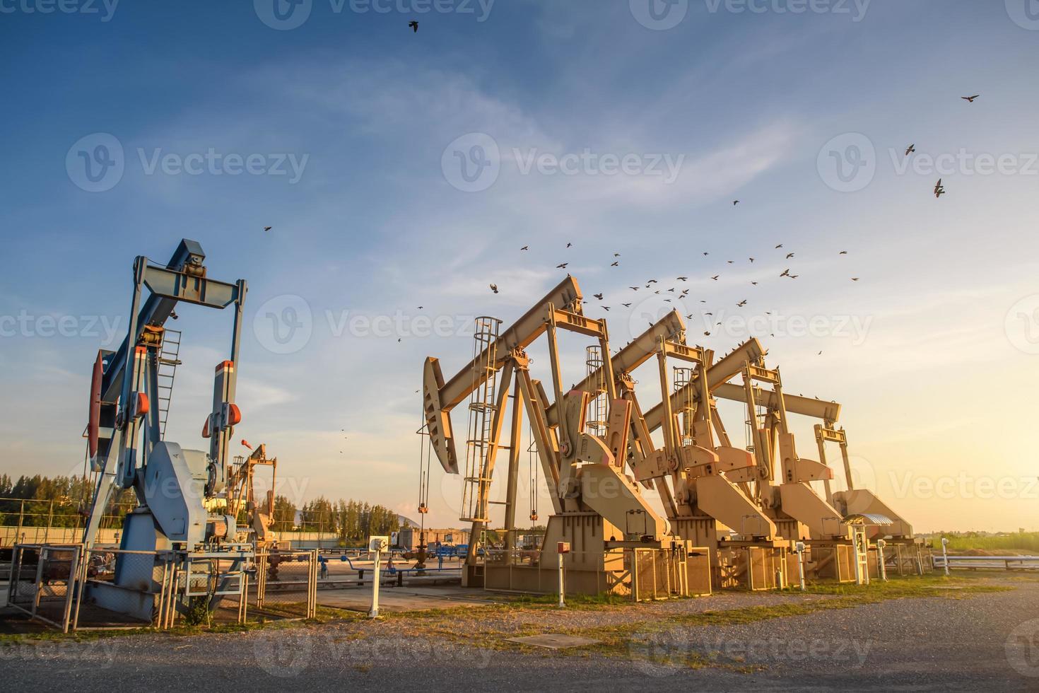 plataforma petrolera o sitio de campo petrolífero, por la mañana o por la noche, las bombas de aceite están funcionando, la bomba de aceite y la hermosa puesta de sol o amanecer de la unidad de bombeo. foto