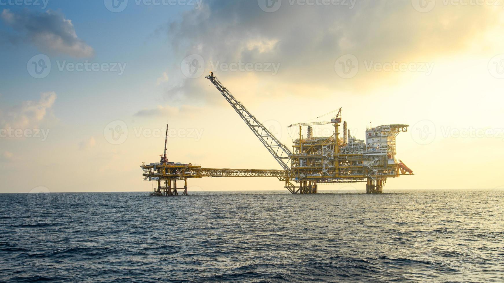 Offshore oil and rig platform in sunset or sunrise time. Construction of production process in the sea. Power energy of the world. photo