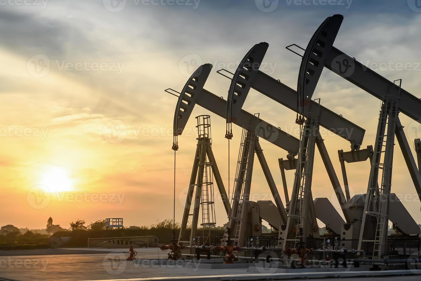 plataforma petrolera o sitio de campo petrolífero, por la mañana o por la noche, las bombas de aceite están funcionando, la bomba de aceite y la hermosa puesta de sol o amanecer de la unidad de bombeo. foto