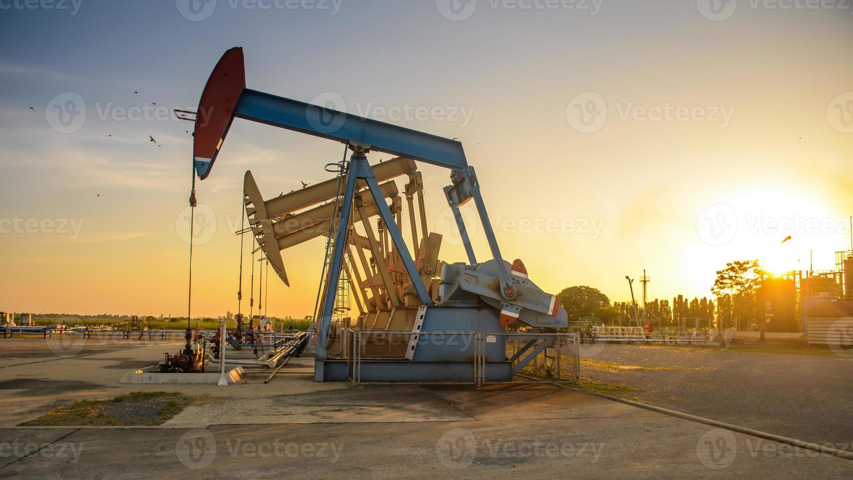 Oil field site, in the evening, oil pumps are running, The oil pump and the beautiful sunset of pumping unit in the evening. photo