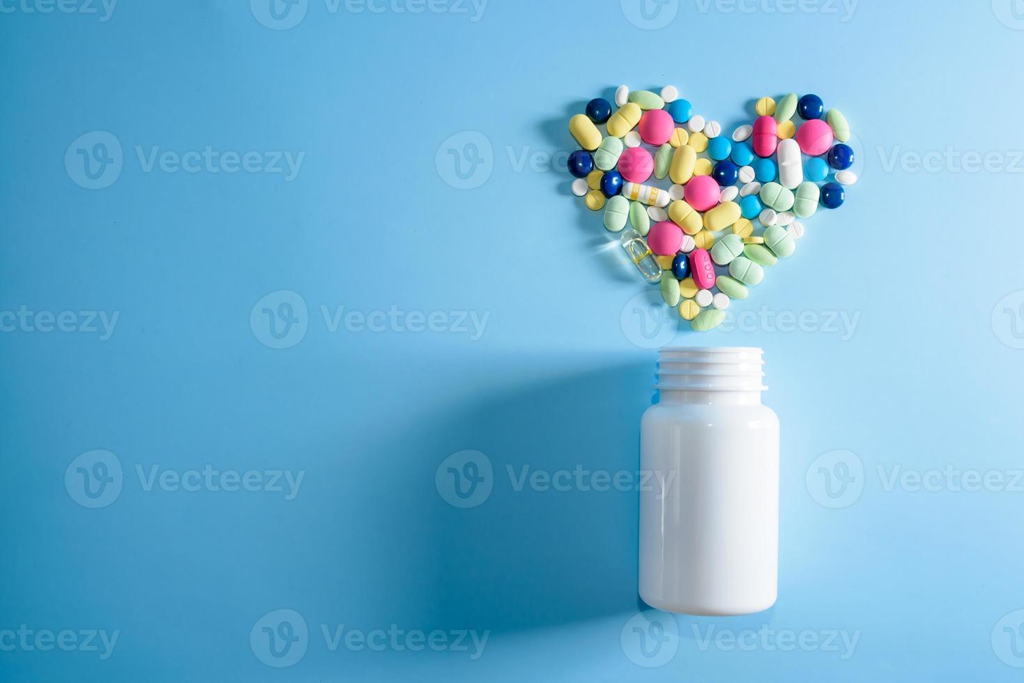 Assorted pharmaceutical medicine pills, tablets and capsules for the treatment of heart disease. Heart shape and bottle of pills. Copy space for text photo