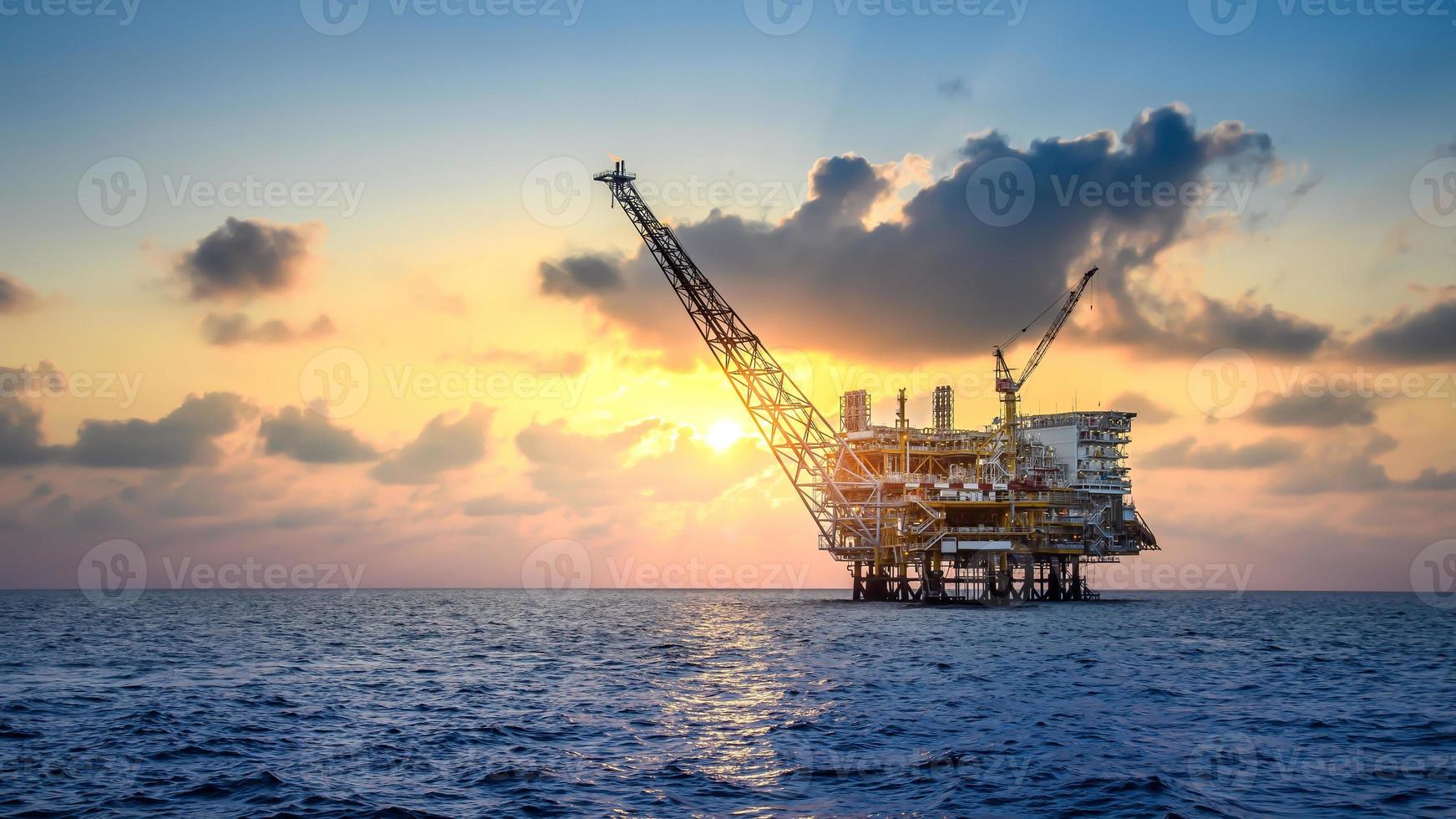 Offshore oil and rig platform in sunset or sunrise time. Construction of production process in the sea. Power energy of the world. photo