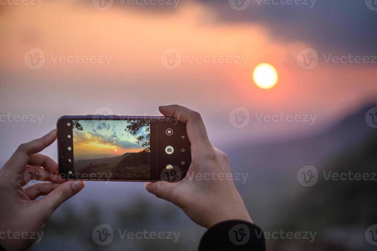 manos de mujer sosteniendo el teléfono móvil para tomar la foto del atardecer