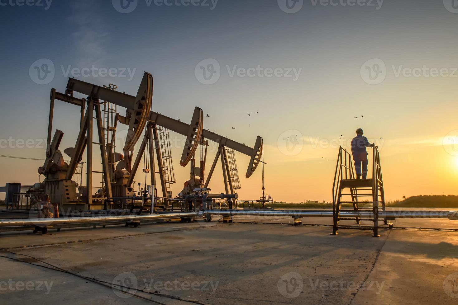 silueta de trabajadores petroleros que trabajan en plataformas petrolíferas o campos petroleros y gasolineras por la noche con una hermosa puesta de sol. foto
