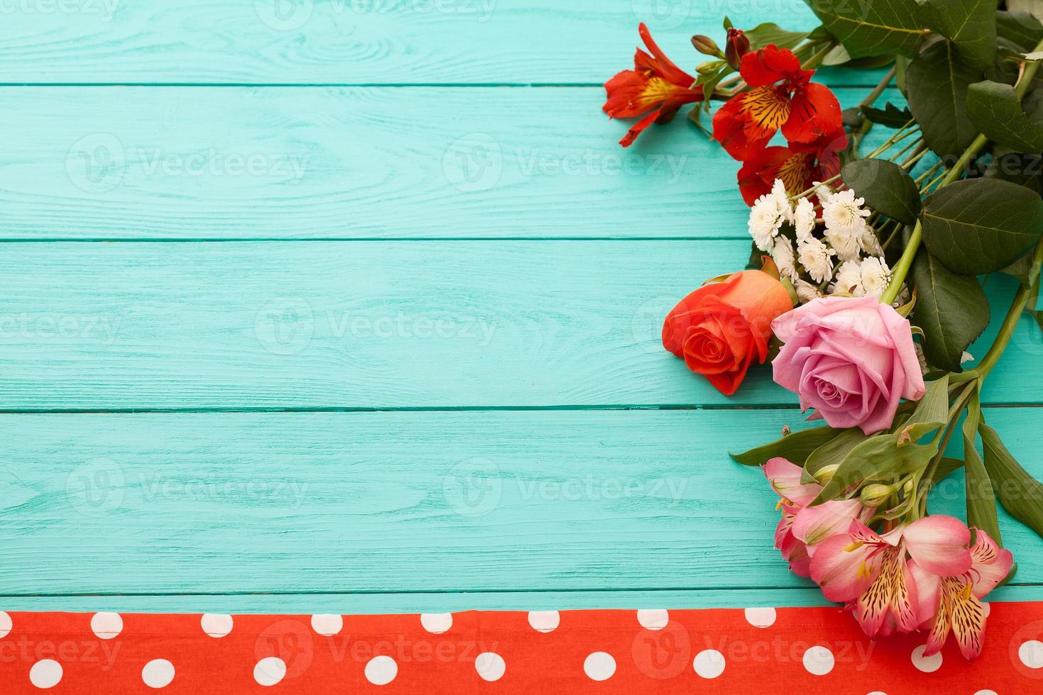 Frame of flowers and towels in polka dots on blue wooden background. Top view and selective focus. Copy space photo