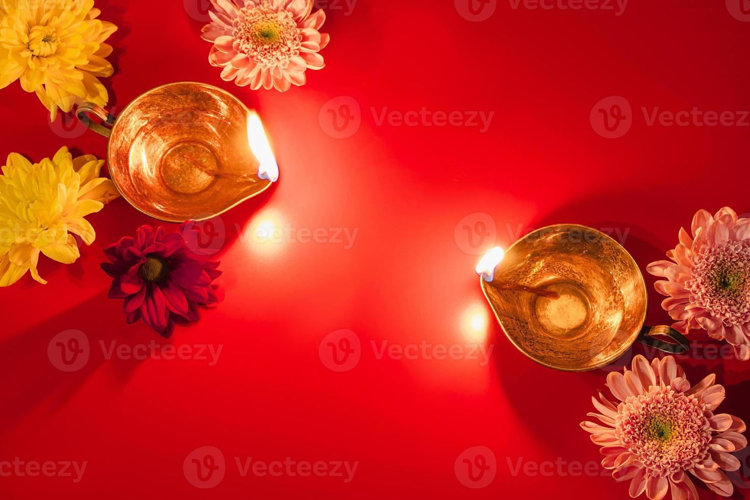 Happy Diwali. Traditional Hindu celebration. Diya oil lamps and flowers on red background. Religious holiday of light. photo